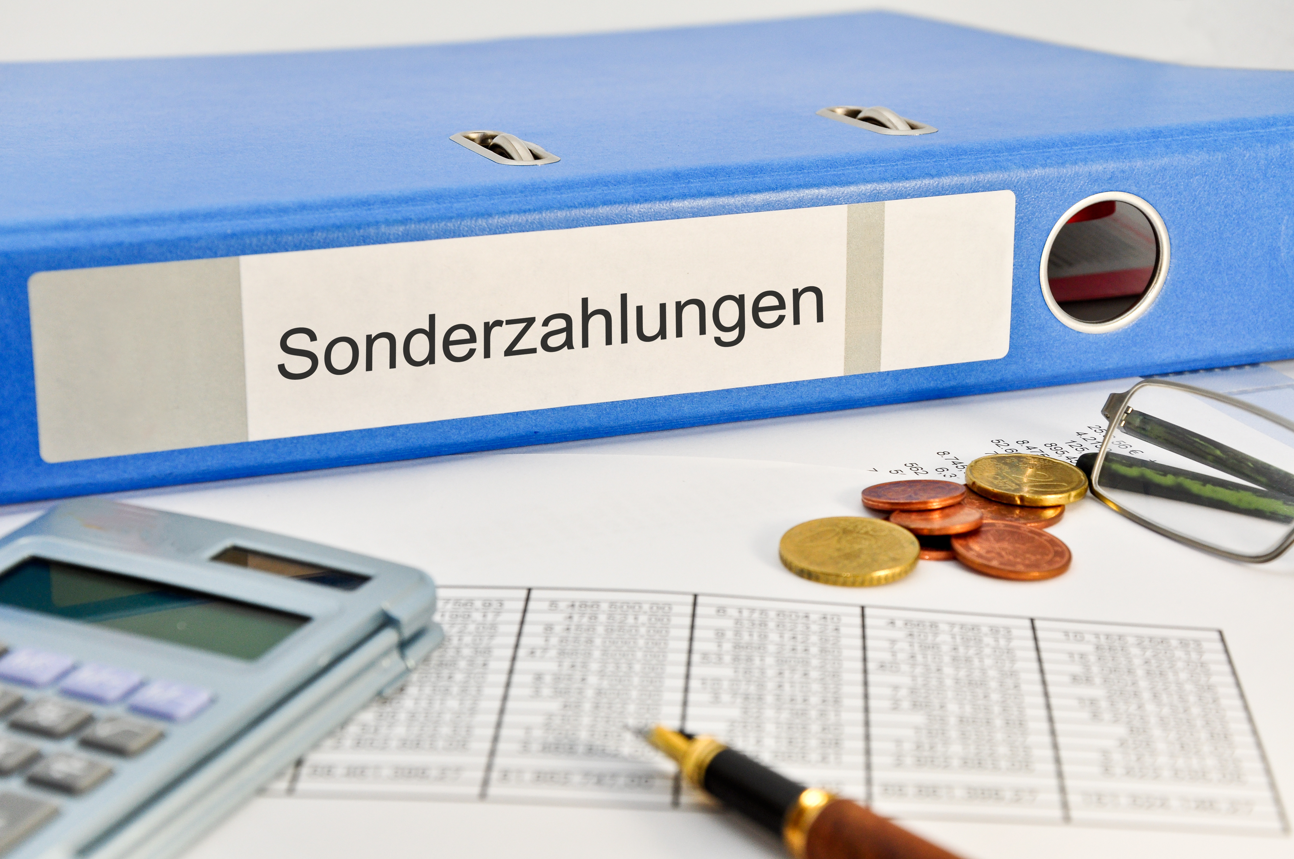 Ordner mit Beschriftung Sonderzahlungen, Taschenrechner und Münzen